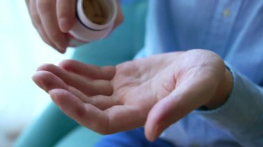 Yaşlı yetişkin bir adam, elinde erkek eline ağrı kesici hapları tutarak ilaç şişesinden iki kapsül dolduruyor, yaşlı büyükanne sağlık hizmetleri, eczane ve tedavi konsepti, yakın görüş..