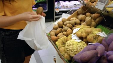 Çekici genç kadın patates seçiyor, süpermarketten alışveriş yapıyor, sağlıklı yiyecekler alıyor, marketten patates alıyor, süpermarketten alıyor. Market konsepti