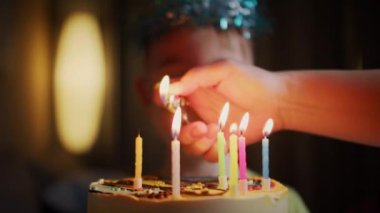 Masada oturan küçük bir çocuğun defocus portresi, doğum günü pastasındaki mumların üzerindeki oğlunun annesi. Evde doğum gününü kutlayan portre çocuğu.