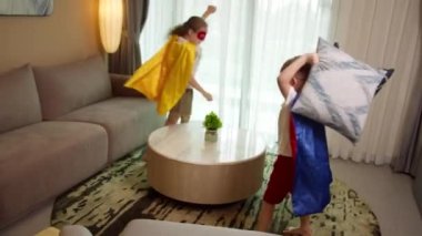 Süper kahramancılık oynayan çocuklar, yastık savaşı yapan çocuklar, kırmızı ve mavi takım elbiseli iki çocuk Supermen, süper kahramanlar, erkek kardeşler, kız kardeşler, evde oynayanlar,