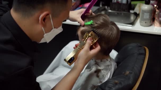 时髦理发师在理发店里用剪子剪头发的孩子 男人发型师和理发沙龙 用修剪器梳理头发 理发师在理发店理发 — 图库视频影像