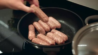 Tavada et sosisi pişirmek. Bir kadın kahvaltıda pişirmek için tavaya sosis koyar. Yemek pişirme süreci