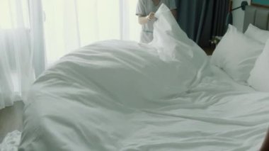 Çalışanlar, otelin iki hizmetçisi, müşteri odasındaki yatağı profesyonel olarak hazırlıyorlar. Beş yıldızlı otel konsepti ve kaliteli oda servisi. Kadınlar odadaki çarşafları değiştiriyor.