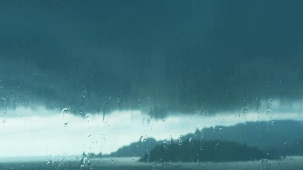 夏のシャワーの間に大きな雨滴が窓ガラスを打つ ガラスの水滴 離れて行く 雨が降る ドロップウィンドウ — ストック動画