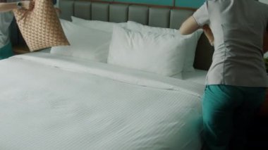 Kadınlar odadaki yatağı değiştiriyor. Çalışanlar, iki otel hizmetçisi, profesyonel olarak müşteri odasındaki yatağı yapıyor. Beş yıldızlı otel konsepti ve kaliteli oda servisi