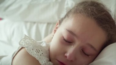 Yanaklarından büyük yaşlar süzülen küçük bir kızın portresi, çocuk evde annesinin yanında yatıyor ve ağlıyor, gözyaşları çığlık çığlığa akıyor..