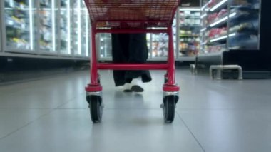 Yavaş çekimde bir süpermarkette alışveriş arabasını iten kadına yaklaş. Market alışverişi kavramı