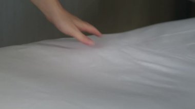 Hizmetçi otel odasını toparlıyor ve sakinleri için birkaç temiz havlu getiriyor. Yakın plan çekimler, temiz beyaz banyo havlularını çarşafa seriyor. Oda hizmetçisi otel odasını temizliyor.