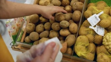 Çekici genç kadın patates seçiyor, süpermarketten alışveriş yapıyor, sağlıklı yiyecekler alıyor, marketten patates alıyor, süpermarketten alıyor. Market konsepti