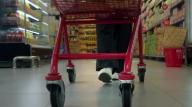 Yavaş çekimde bir süpermarkette alışveriş arabasını iten kadına yaklaş. Market alışverişi kavramı