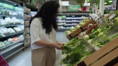 Pembe takım elbiseli çekici genç kadın lahana salatası seçiyor, süpermarketten alışveriş yapıyor, bakkaldan sağlıklı yiyecekler alıyor, marketten lahana salatası alıyor, süpermarketten. Market alışverişi kavramı