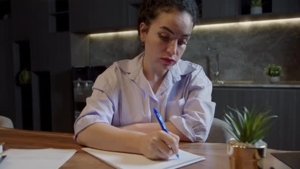 机に座っている白人女性は 日記にペンのメモを書き ビューを閉じます ビジネスウーマンは 起業のアイデアや計画 創造的な考えをノートブックに書き込みます Doまたはウィッシュリストの作成 — ストック動画
