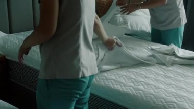Kadınlar odadaki yatağı değiştiriyor. Çalışanlar, iki otel hizmetçisi, profesyonel olarak müşteri odasındaki yatağı yapıyor. Beş yıldızlı otel konsepti ve kaliteli oda servisi