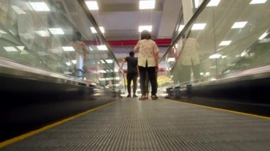 Nha Trang, Vietnam, 11 Ağustos 2022: Asyalılar modern alışveriş merkezinde yürür ve yürüyen merdiven kullanır. Umumi alışveriş merkezi, modern Asya 'daki günlük şehir hayatı ya da banliyö yaşam tarzı kavramı. Yürüyen merdivendeki insanlar.