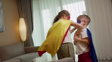 Süper kahramancılık oynayan çocuklar, zıplayan çocuklar, kırmızı ve mavi takımlı çocuklar Supermen, süper kahramanlar, kardeş, evde oynayan çocuklar, süper kahraman oldukları için çıldırıyorlar..
