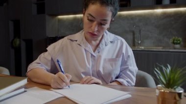 Masasında oturan beyaz bir kadın elinde kalemle günlüğe not alıyor, manzarayı kapatıyor. İş kadını yeni başlayan iş fikirleri ve planlar yazar. Not defterine yaratıcı düşünceler yazar. Yapılacaklar ya da istekler listesi oluştur