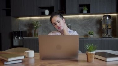 Kapalı bir kadın iş yerinde oturur ve boyun ağrısını hisseder. Kas gerilimini azaltmak için ovuşturur. Servikal osteokondroz, aşırı çalışan yorgun kadın, yerleşik yaşam tarzı konsepti