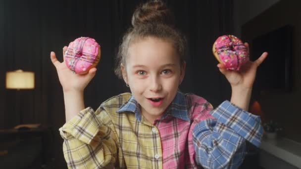 Retrato Niño Caucásico Con Una Camisa Rosa Sostiene Dos Rosquillas — Vídeos de Stock