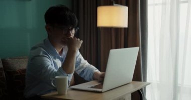 Genç, çekici Asyalı Vietnamlı iş bilgisayarı ya da akıllı tablet evdeki masada serbest veri analisti, veri bilimci iş adamı