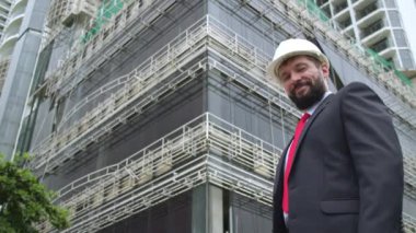 Güvenlik Üniforması ve Sert Şapka Giyen Profesyonel Kafkas Mühendis İşçi Portresi. Şema çizim planı, şema planı, şema çizimleri kullanır. Kendinden emin Kafkasyalı Endüstri Uzmanı