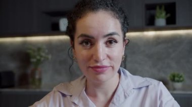 Ofisteki kameraya bakan kendinden emin, genç, Avrupalı bir kadın. Beyaz dişli, güzel yüzlü, kapalı mekan portresi için poz veren mutlu kadın.