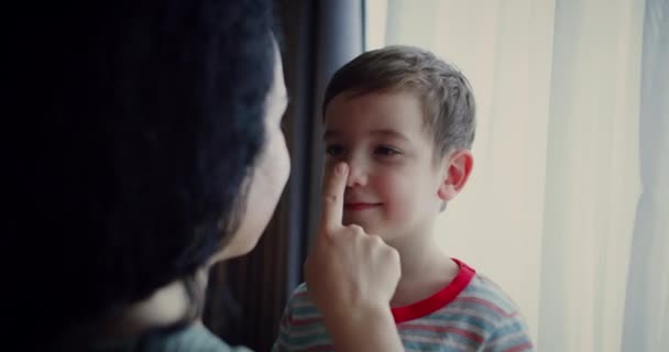 母親と息子の肖像画 母親は彼女の指で彼女の笑顔の息子の鼻をストロークし 子供は目を愛する母親を見て笑顔で満足しています 母と息子の日の概念 — ストック動画