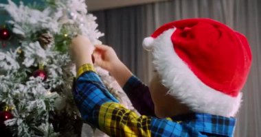 Mutlu küçük kız Noel ağacını toplarla süslüyor. Ağacın altında bir sürü hediye kutusu var. Çocuklar Noel ağacı süslüyorlar. Noel 'de Noel ağacının yanında bir çocuğun portresi