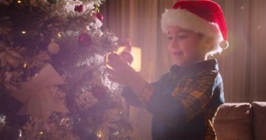 Mutlu küçük kız Noel ağacını toplarla süslüyor. Ağacın altında bir sürü hediye kutusu var. Çocuklar Noel ağacı süslüyorlar. Noel 'de Noel ağacının yanında bir çocuğun portresi