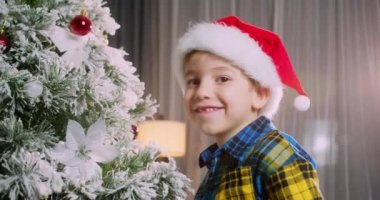 Mutlu küçük kız Noel ağacını toplarla süslüyor. Ağacın altında bir sürü hediye kutusu var. Çocuklar Noel ağacı süslüyorlar