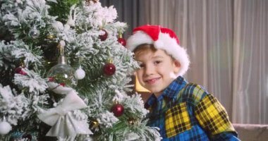 Mutlu küçük kız Noel ağacını toplarla süslüyor. Ağacın altında bir sürü hediye kutusu var. Çocuklar Noel ağacı süslüyorlar