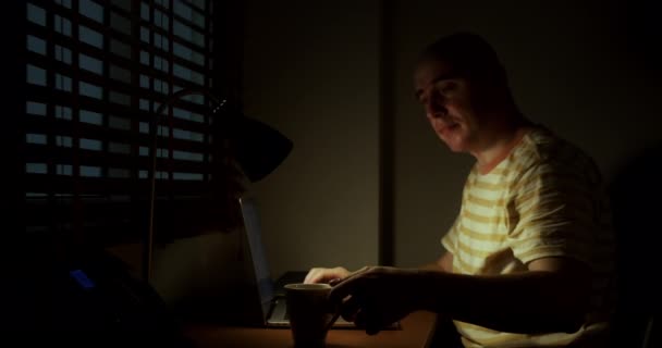 在办公室工作的男性在笔记本电脑边工作 边喝咖啡 办公室职员在互联网上加班 商人在笔记本电脑上加班 — 图库视频影像