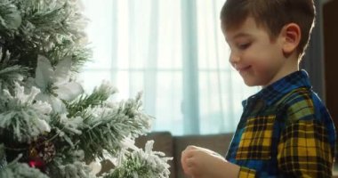 Mutlu küçük kız Noel ağacını toplarla süslüyor. Ağacın altında bir sürü hediye kutusu var. Çocuklar Noel ağacı süslüyorlar