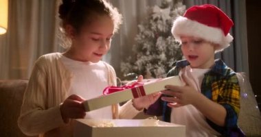 Mutlu şirin çocuklar, süprizden zevk alır, bir Noel hediyesi kutusunu açar ve hediyesinden aldığı mutlulukla yere düşer. Portre güzel küçük çocuk, çocuk Noel sürprizi ile kutuyu açıyor..
