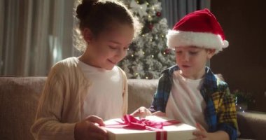 Mutlu şirin çocuklar, süprizden zevk alır, bir Noel hediyesi kutusunu açar ve hediyesinden aldığı mutlulukla yere düşer. Portre güzel küçük çocuk, çocuk Noel sürprizi ile kutuyu açıyor..