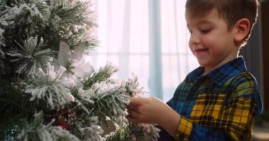 Mutlu küçük kız Noel ağacını toplarla süslüyor. Ağacın altında bir sürü hediye kutusu var. Çocuklar Noel ağacı süslüyorlar
