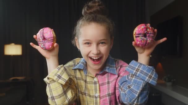 Retrato Niño Caucásico Con Una Camisa Rosa Sostiene Dos Rosquillas — Vídeos de Stock