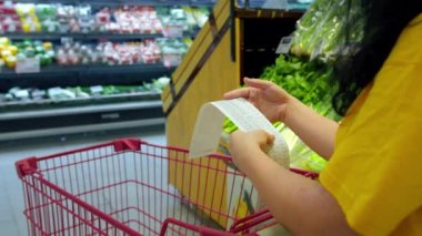 Alışveriş merkezinden alışveriş yaptıktan sonra alışveriş arabasındaki Sevgili Miktar faturasını kontrol eden bir kadın. Gıda fiyatlarında artış, hipermarkette para harcamak