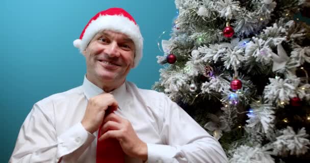 Noel Baba Şapkalı Gülümseyen Bir Adamın Noel Ağacının Arka Planında — Stok video