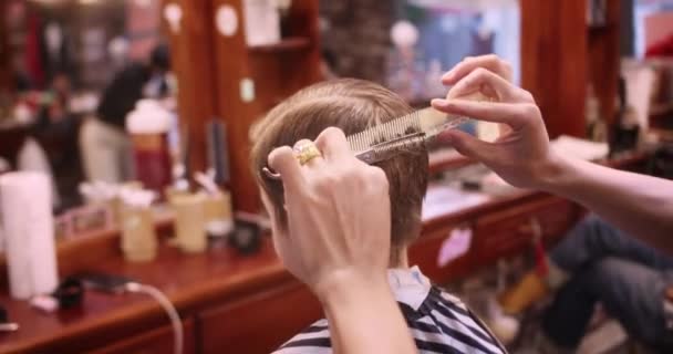 理发师把头发吹得干干净净的 时髦的理发师在理发店里用剪子剪掉小孩的头发 男人的发型和发型在沙龙里 用吹风机护理头发 — 图库视频影像