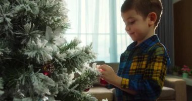 Mutlu küçük kız Noel ağacını toplarla süslüyor. Ağacın altında bir sürü hediye kutusu var. Çocuklar Noel ağacı süslüyorlar