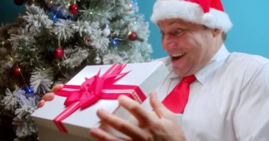 Noel Baba 'nın Noel şapkalı mutlu babası bir hediye alır, bir sürprizle kutuya bakar, babalar şaşırır, mutlu adam yüzü, sürprizle mutlu olur, hediyelerle kutuyu açar.