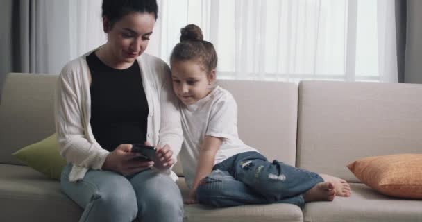 엄마와 비디오를 아이가 엄마는 소파에 스마트폰을 생활의 기술을 즐긴다 — 비디오