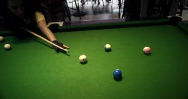 Yedi numaralı mavi topu bir cebe sokuyor. Bilardo topları yeşil masaya saçıldı. Bilardo oyunu yeşil kumaş üzerine. Uzaktan görülen beyaz bilardo topu