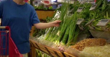 Çekici genç kadın yeşil soğan seçiyor, süpermarketten alışveriş yapıyor, sağlıklı yiyecekler alıyor, marketten yeşil soğan alıyor, süpermarketten. Market kavramı