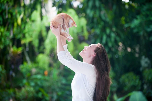 Donna asiatica solleva un gatto rosso nel parco — Foto Stock