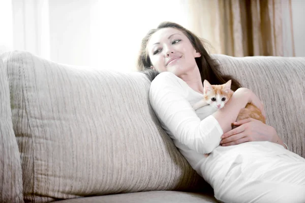 Mulher asiática deitada no sofá com gato vermelho — Fotografia de Stock