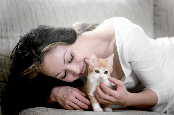 Asyalı kadın kanepe kırmızı kedi ile yalan söylüyor. — Stok fotoğraf