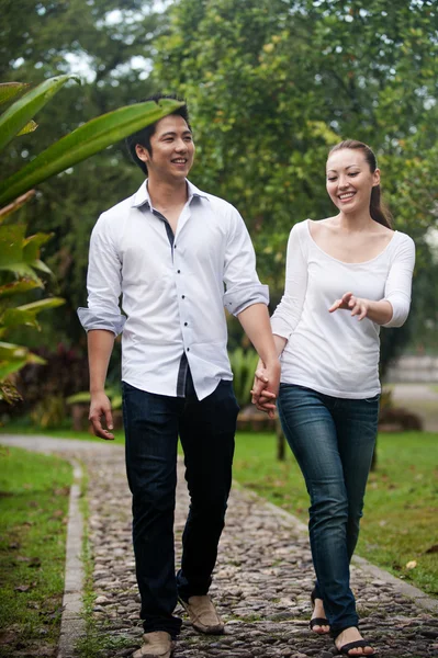 Asian couple holding hands walking on the park path — Stock Photo, Image