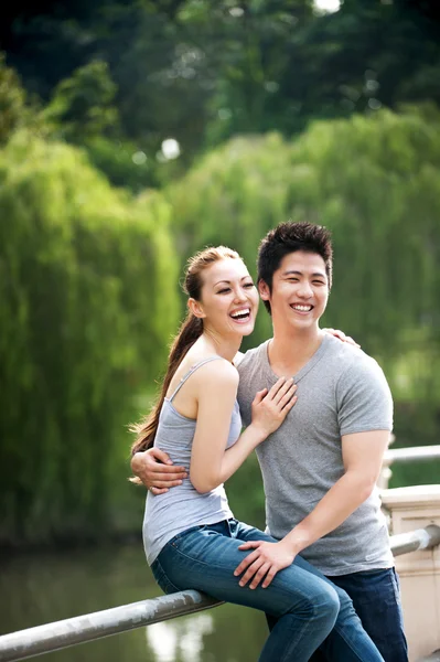 Asian couple sitting on embankment in the park — Stock Photo, Image