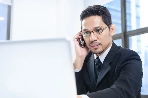 Hombre de negocios usando teléfono celular y portátil — Foto de Stock